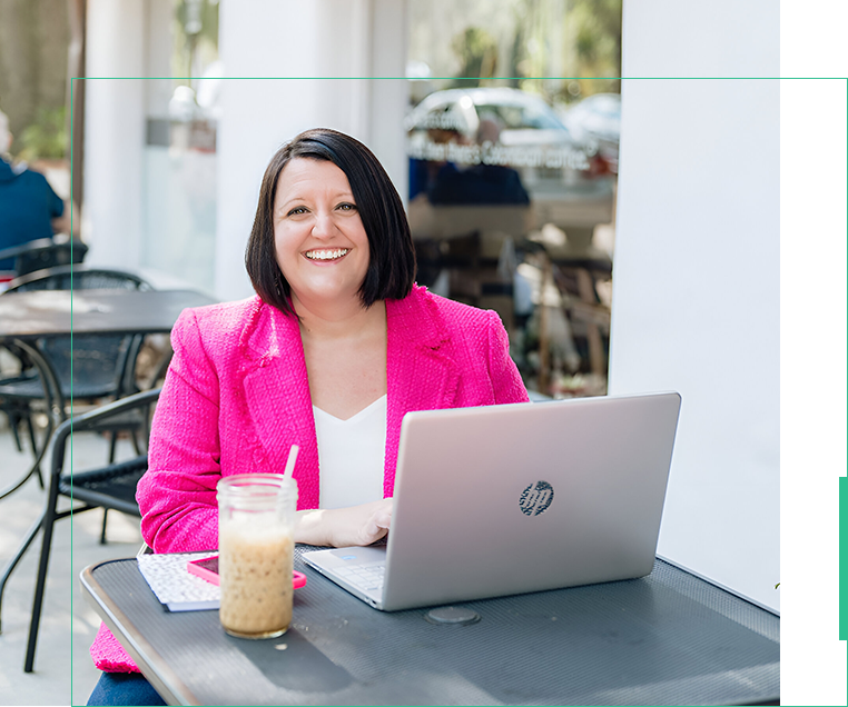 A woman sitting at an outdoor table with a laptop.