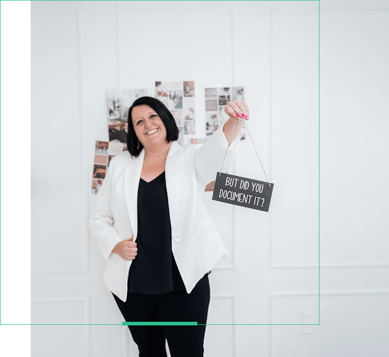 A woman holding up a sign in front of a wall.