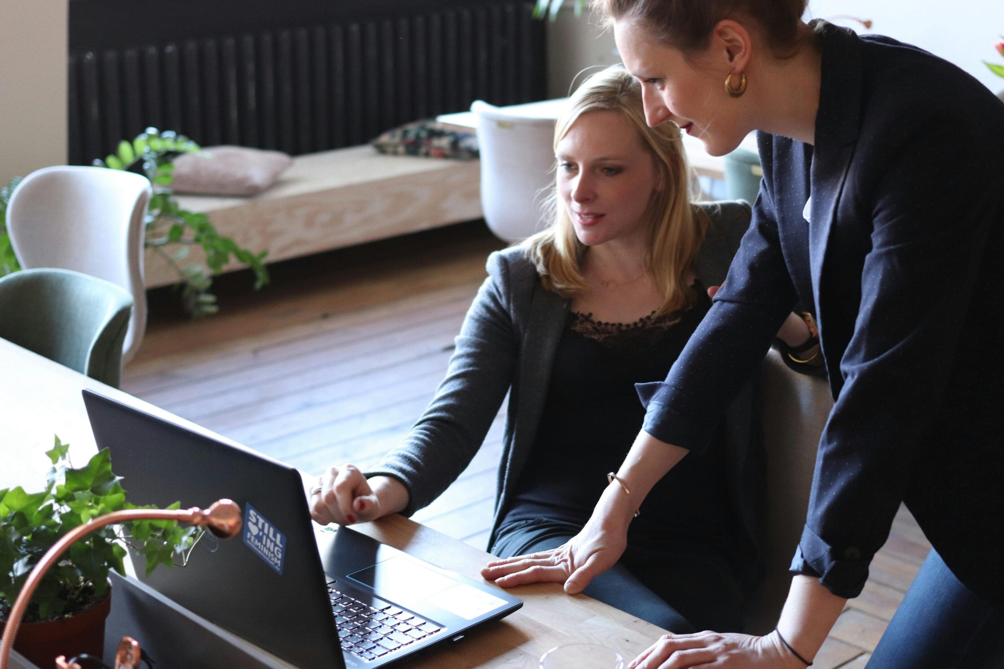 Two people looking at a laptop on the floor