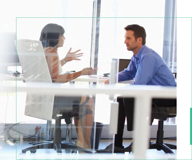 Two people sitting at a table talking to each other.