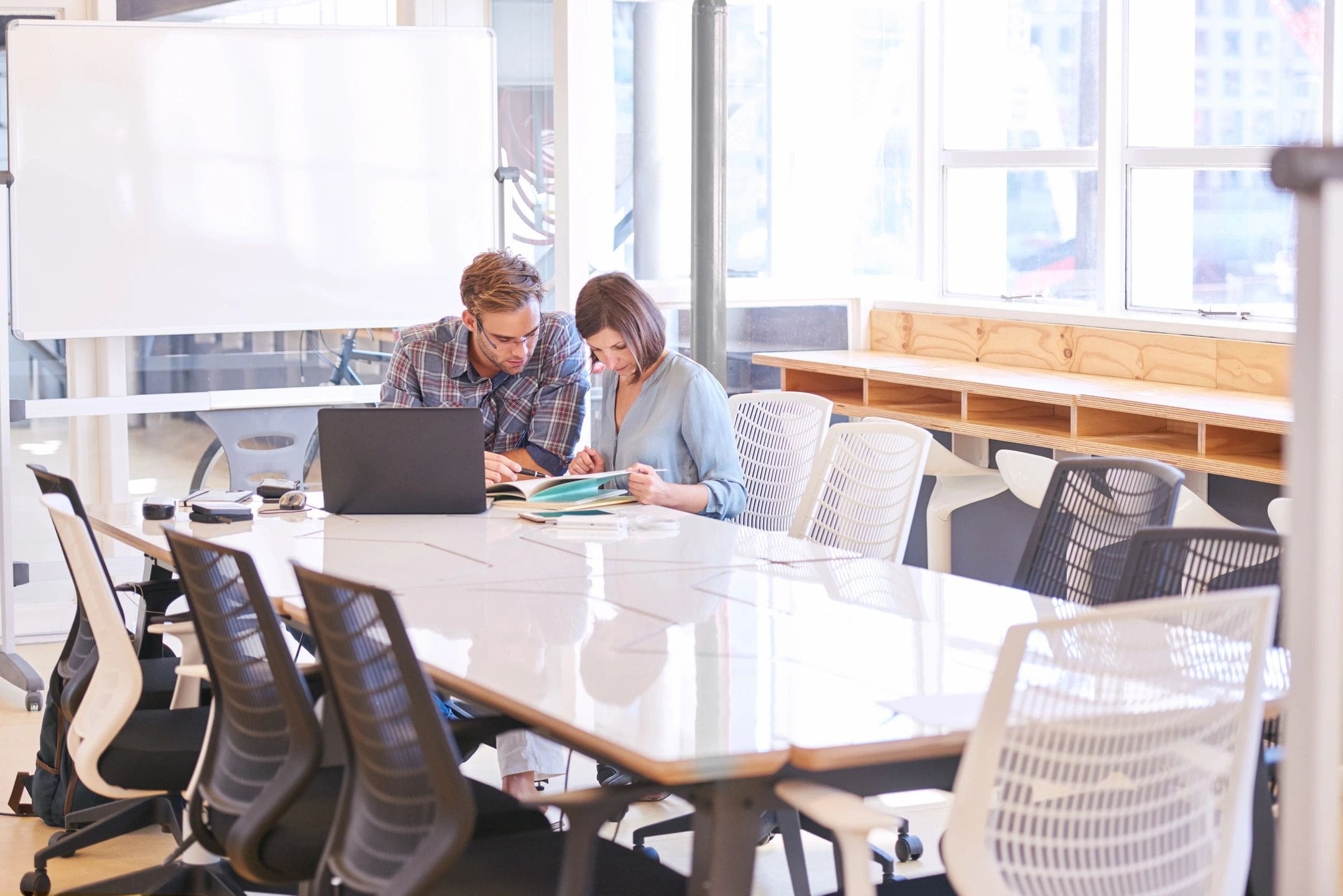 Two people are sitting at a table looking at papers.