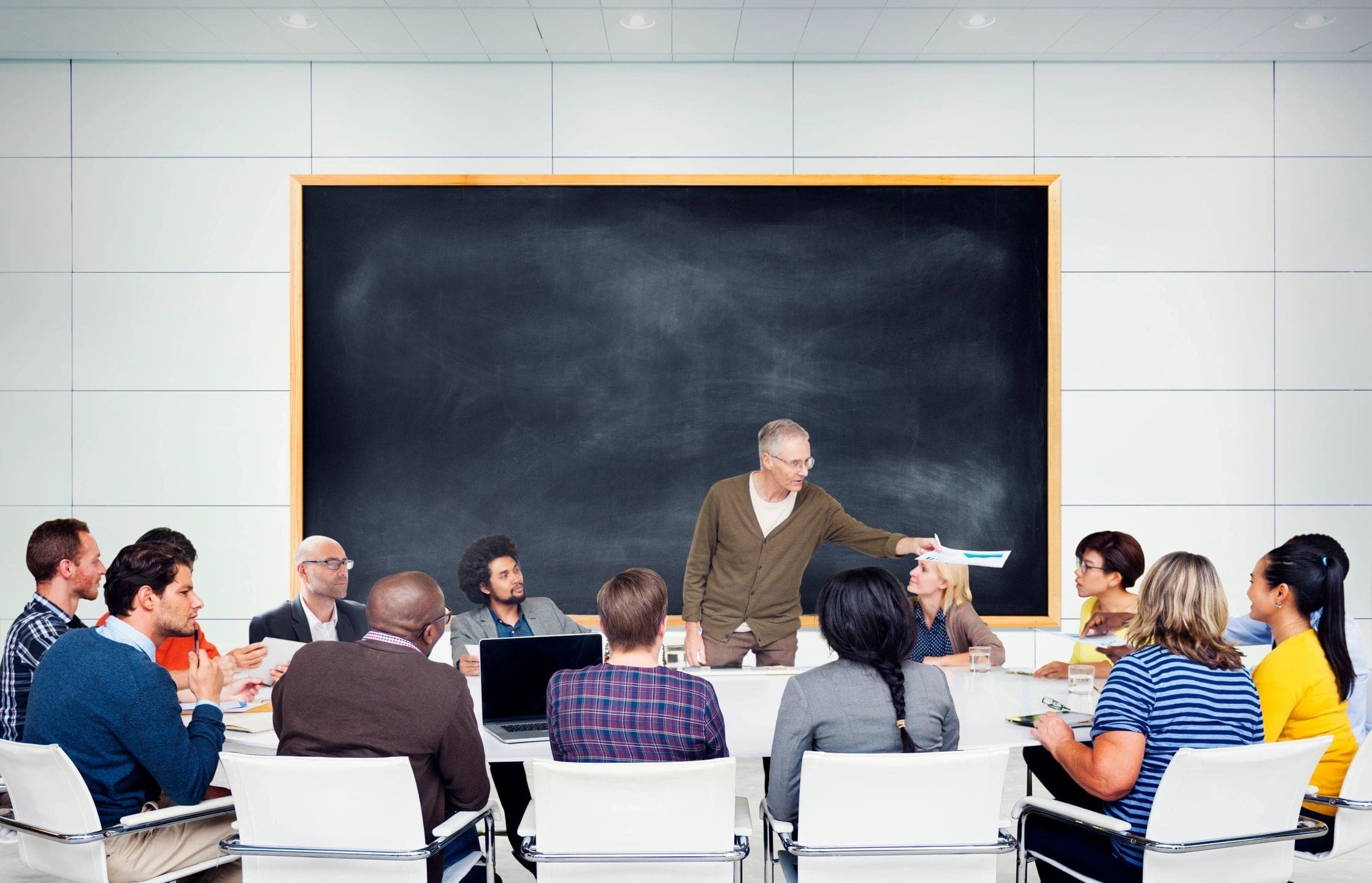 A group of people sitting at tables in front of a chalkboard.