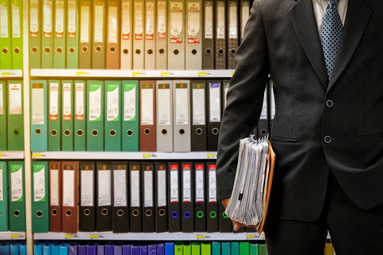 A man in suit and tie holding a folder.